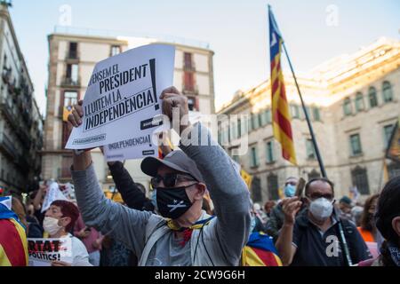 A Catalan pro-independence protester wearing a protective mask is seen showing a placard that says 'we defend the president, we fight for independence' during the protest.The Superior Court of Justice of Catalonia condemned the president of Catalonia, Quim Torra, with disqualification, for refusing to remove a banner in favor of Catalan political prisoners as ordered by the Central Electoral Board. Stock Photo