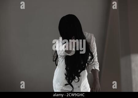 Girl zombie in blood. Asian Woman ghost with blood. Horror scary fear in house dark tone raise hand and reach out. Closeup hair covering the face her Stock Photo