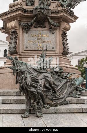 Quito, Ecuador - December 2, 2008: Historic downtown, Plaza Grande. Closeup of lion with flags and cross bronze statue at foot of Independence Monumen Stock Photo