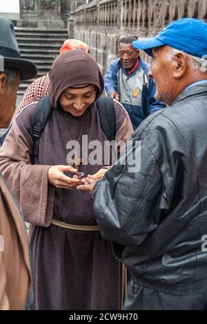 Quito, Ecuador - December 2, 2008: Historic downtown. Closeup of Young Monk in brown habit cuts nails of homeless men. Stock Photo