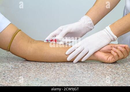 Blood test from venous vein  of patient by female doctor in white medical gloves on   the marble table Stock Photo