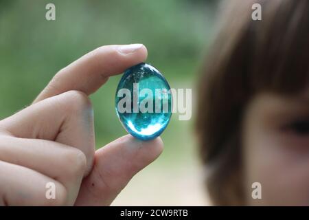 Crystal glass ball in human hand on defocused grass background. Saving environment, save clean green planet, ecology concept Stock Photo