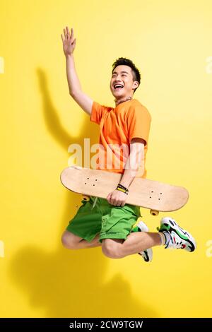 Holding a skateboard bouncing young man Stock Photo