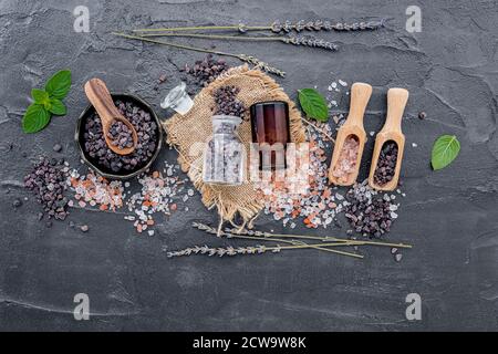 Himalayan black salt and Himalayan pink salt with peppermint and lavender flower on dark concrete background. Himalayan salt commonly used in cooking Stock Photo