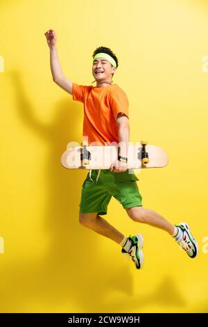 Holding a skateboard bouncing young man Stock Photo