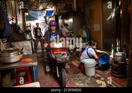 A motorbike cuts through a restaurant kitchen on a walkway that dissects this eatery in Bangkok's Chinatown. Stock Photo