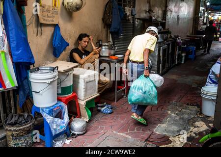 An elderly man carrying a green bag makes his way along a walkway that dissects this Chinatown restaurant. Stock Photo