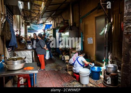 A motorbike cuts through a restaurant kitchen on a walkway that dissects this eatery in Bangkok's Chinatown. Stock Photo