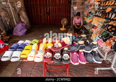 A woman relaxes while waiting for customers to visit her Chinatown shoe store in Bangkok. Stock Photo