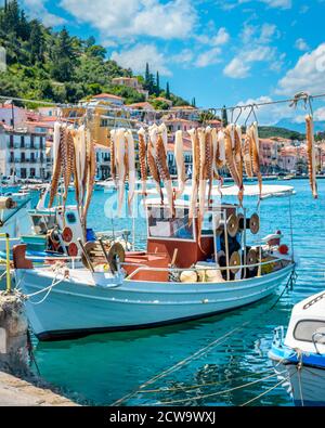 view of octopus tentacles hanging in the sun and traditional fishing boats on the port of picturesque Gythio town Greece