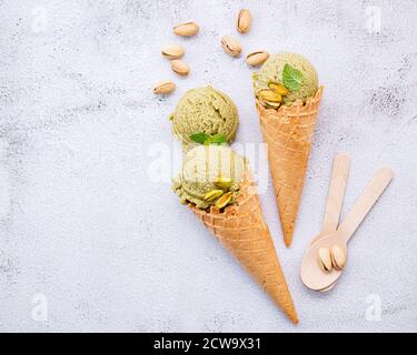 Pistachio ice cream in cones  with pistachio nuts setup on white stone background . Summer and Sweet menu concept. Stock Photo