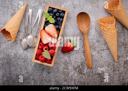 Waffle cones with berries in wooden box setup on concrete background. Summer and Sweet menu concept. Stock Photo
