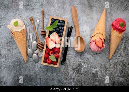 Various of ice cream flavor in cones with berries in wooden box setup on concrete background . Summer and Sweet menu concept. Stock Photo