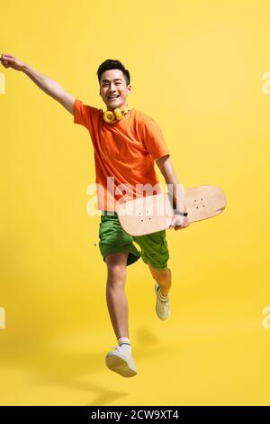 Holding a skateboard bouncing happy young man Stock Photo