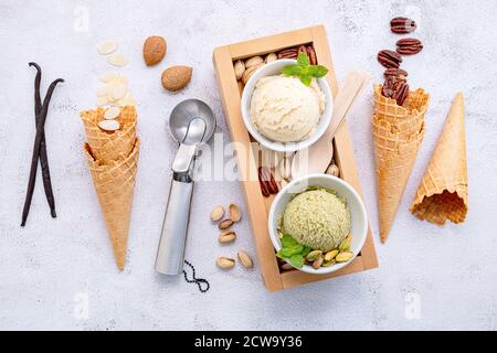 Pistachio and vanilla ice cream in bowl  with mixed nuts setup on white stone background . Summer and Sweet menu concept. Stock Photo