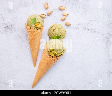 Pistachio ice cream in cones  with pistachio nuts setup on white stone background . Summer and Sweet menu concept. Stock Photo