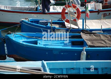 blue fishermen boats moored at the pier in the port of Trani in Apulia South Italy in a summer daylight Stock Photo