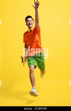 Holding a skateboard bouncing happy young man Stock Photo