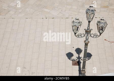 one vintage street lamp and shadow top view on the stone sidewalk in the town of Trani in South Italy in a sunny summer day Stock Photo