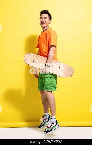Holding a skateboard happy young man Stock Photo