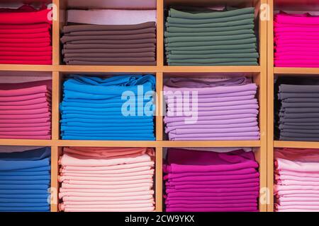 Wooden wardrobe with different colours clothes display in a clothes shop. Stock Photo
