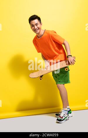 Holding a skateboard happy young man Stock Photo