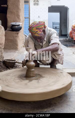 Indian man shaping clay using a potters wheel in rural Rajasthan, India Stock Photo