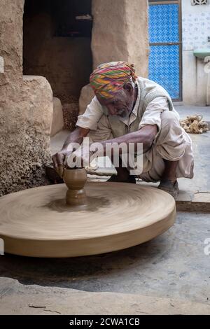 Indian man shaping clay using a potters wheel in rural Rajasthan, India Stock Photo