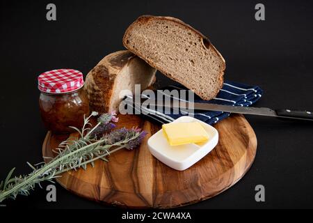 Loaf of rye bread sliced in half on a wooden board with a black background Stock Photo