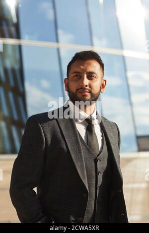 Elegant young bearded businessman in black suit standing in the city outdoors Stock Photo