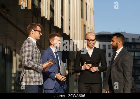 Mature female leader in black suit talking to her team while they standing in the city Stock Photo