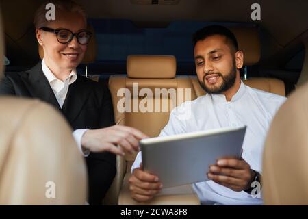 Two business colleagues working online on digital tablet in team while they travelling by car Stock Photo