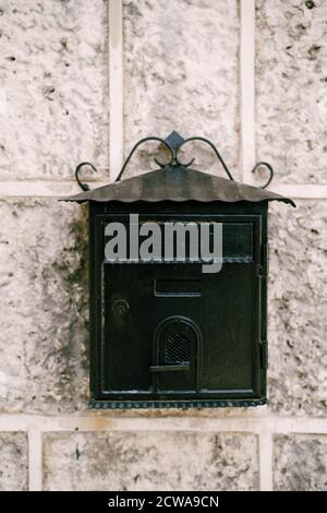 Close-up of a black metal mailbox on a stone wall. Stock Photo