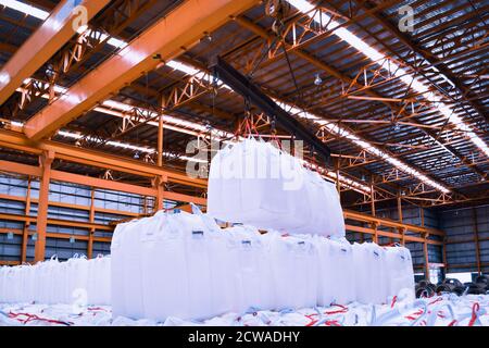 Overhead crane lift jumbo bags of tapioca using spread bar in storage warehouse. Bulk cargo in jumbo bag handling equipment. Stock Photo