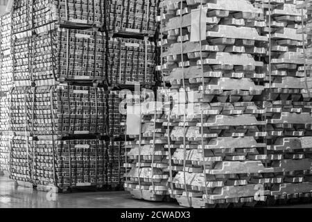 Aluminum ingot bar stacked in warehouse. Raw material for industrial concept. General cargo warehouse concept Stock Photo