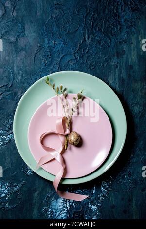 Easter table setting with empty plates with blossom willow branches and golden quail egg. Classic blue texture background. Flat lay, space Stock Photo