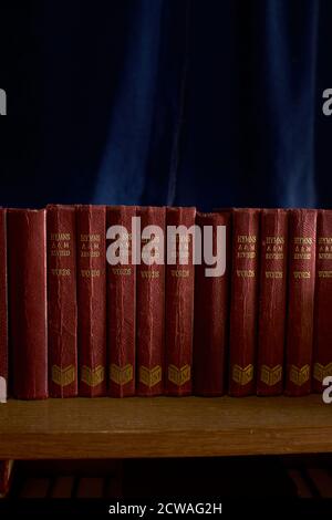 A row of old Hymn Books in a rural church with a blue curtain backdrop. Stock Photo