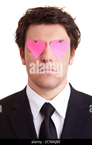 Manager with heart-shaped pink sticky notes in front of his eyes Stock Photo