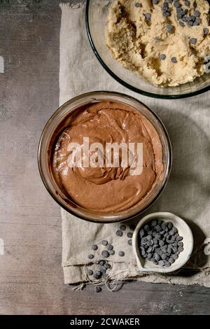 Tow types of dough chocolate and shortbread for home baking trend dessert brookies brownies and cookies in glass bowls, with chocolate chips on linen Stock Photo