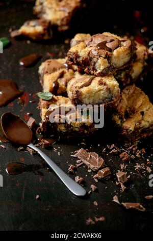 Trend baking Brookies chocolate brownies and cookies homemade cake sliced by squares in row, chocolate sauce, mint on black background. Stock Photo