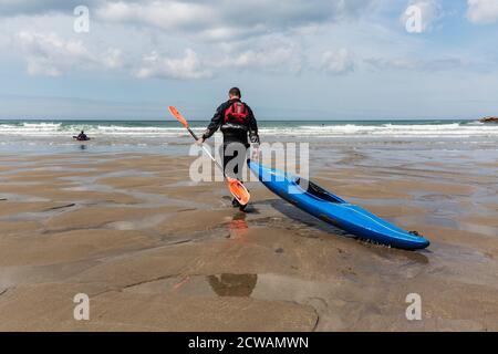 Man pulling his canoe along the beach towards the sea Stock Photo