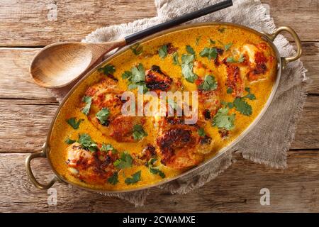 Kenyan Kuku Paka is a chicken roasted over charcoal and then cooked in a coconut curry closeup in the pan on the table. Horizontal top view from above Stock Photo