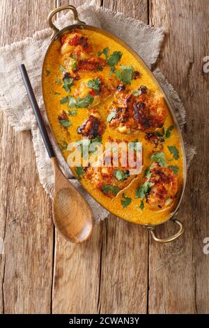 Homemade Kuku Paka is a spicy chicken curry that's cooked in coconut milk and spices closeup in the pan on the table. Vertical top view from above Stock Photo