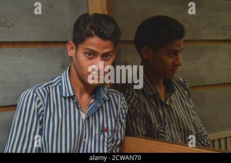 Indian boys giving poses for fashion photo shoot on studio with using specs, headphone, light bulb props. Stock Photo