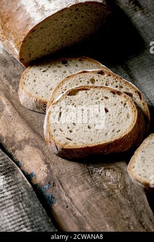 Sliced whole grain artisan rye-wheat organic bread over old wooden background. Close up Stock Photo