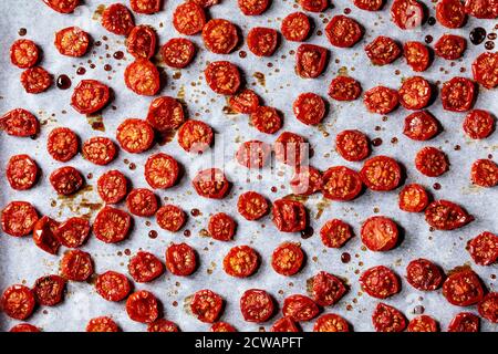 Sun-dried cherry tomatoes with olive oil and balsamic vinegar on baking paper. Top view, food background Stock Photo