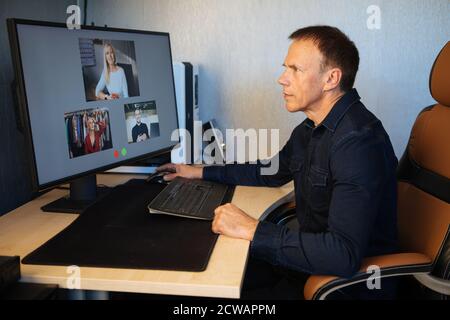 Mature man having video call via computer in the home office. Online team meeting video conference calling from home. Attractive Businessman Telework. Stock Photo
