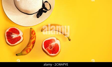 Grapefruit, banana and summer straw hat on a yellow background Stock Photo