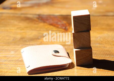 Three wooden blocks, leather wallet, pen on natural solid wood table. Business Marketing concept. Stock Photo