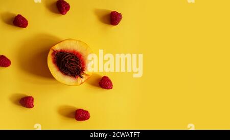 Raspberries and peaches for healthy summer eating - on yellow background Stock Photo